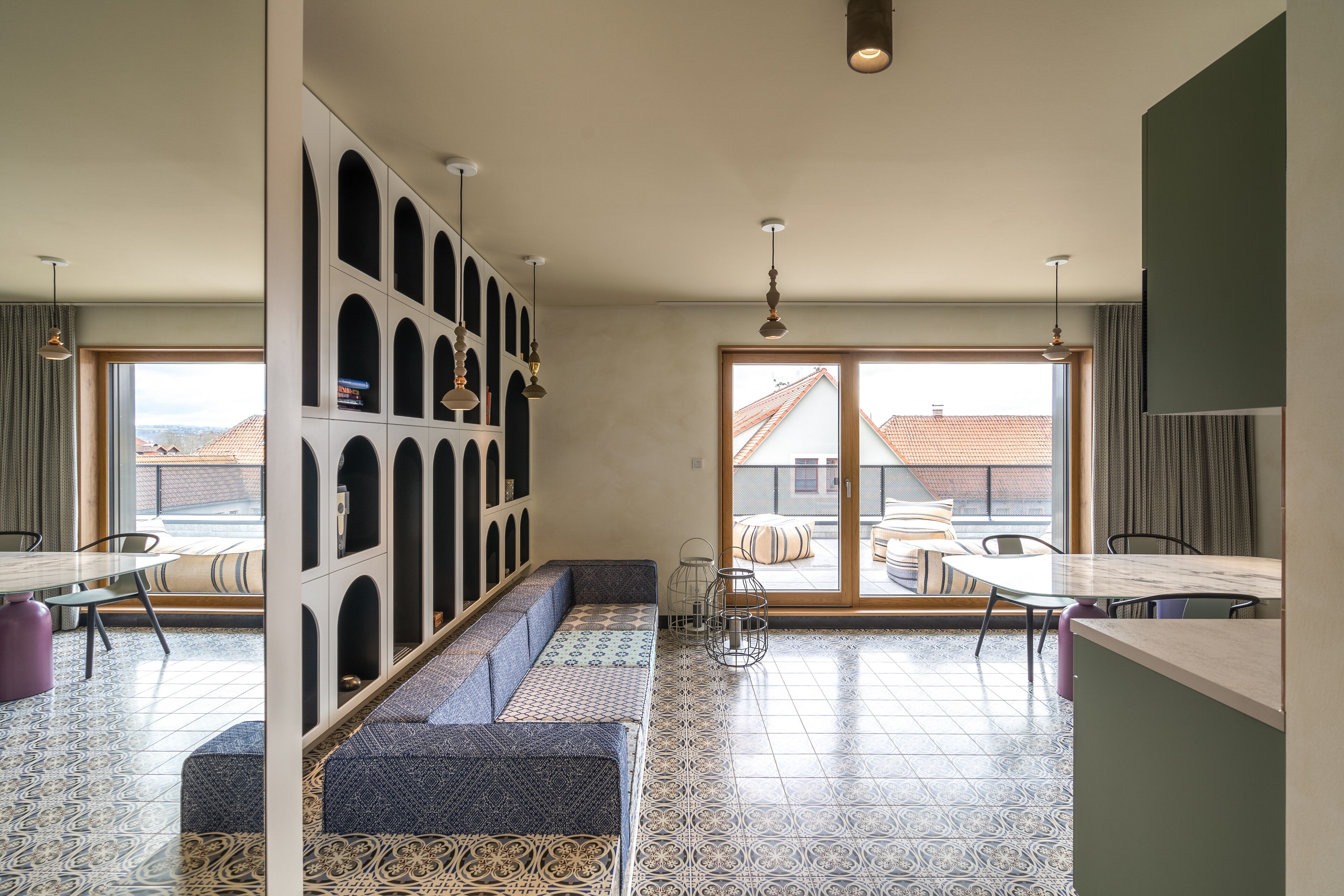 A modern interior with a seating area, a dining space, and a view through a glass door.
