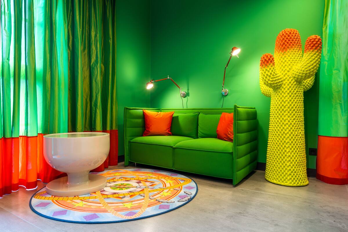 Une pièce avec un canapé vert, une sculpture en forme de cactus et un globe terrestre posé sur un socle.