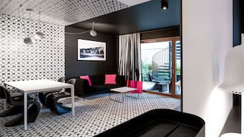 A modern room with a patterned floor, a black sofa with pink cushions, a white table, and a large window with curtains.