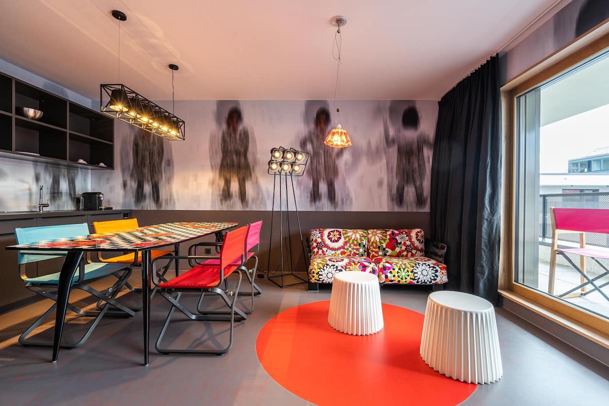 Un intérieur moderne comprenant un coin repas, des sièges aux couleurs vives et de grandes fenêtres.