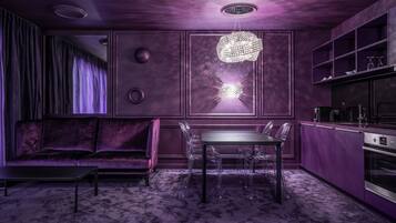 A modern kitchen with a dining area, featuring a purple color scheme, a chandelier, and a built-in oven.