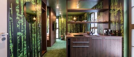 A modern kitchen with a central island, wooden cabinets, and a green carpet.