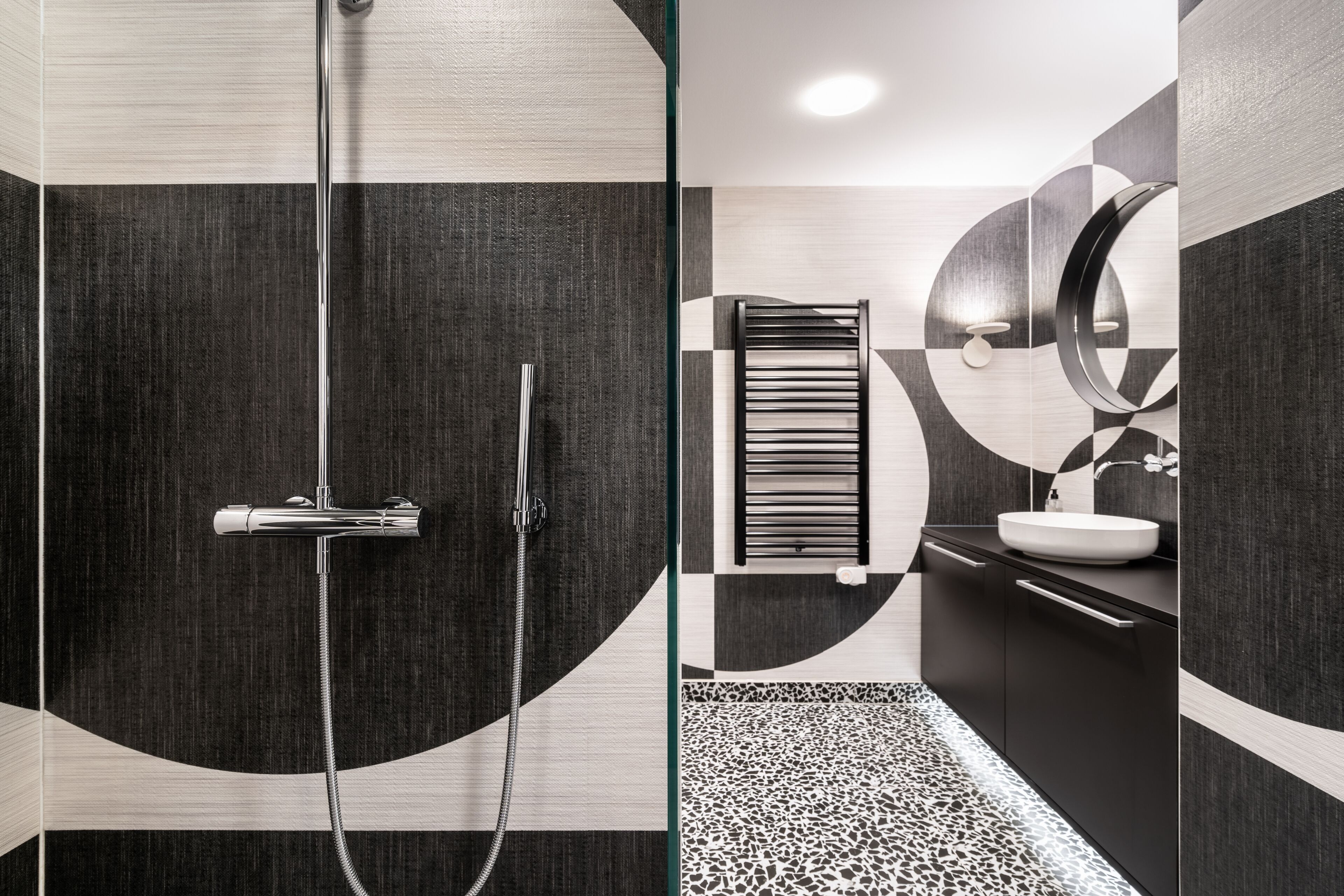 A modern bathroom with a glass shower enclosure, a towel rack, and a sink with a mirror.