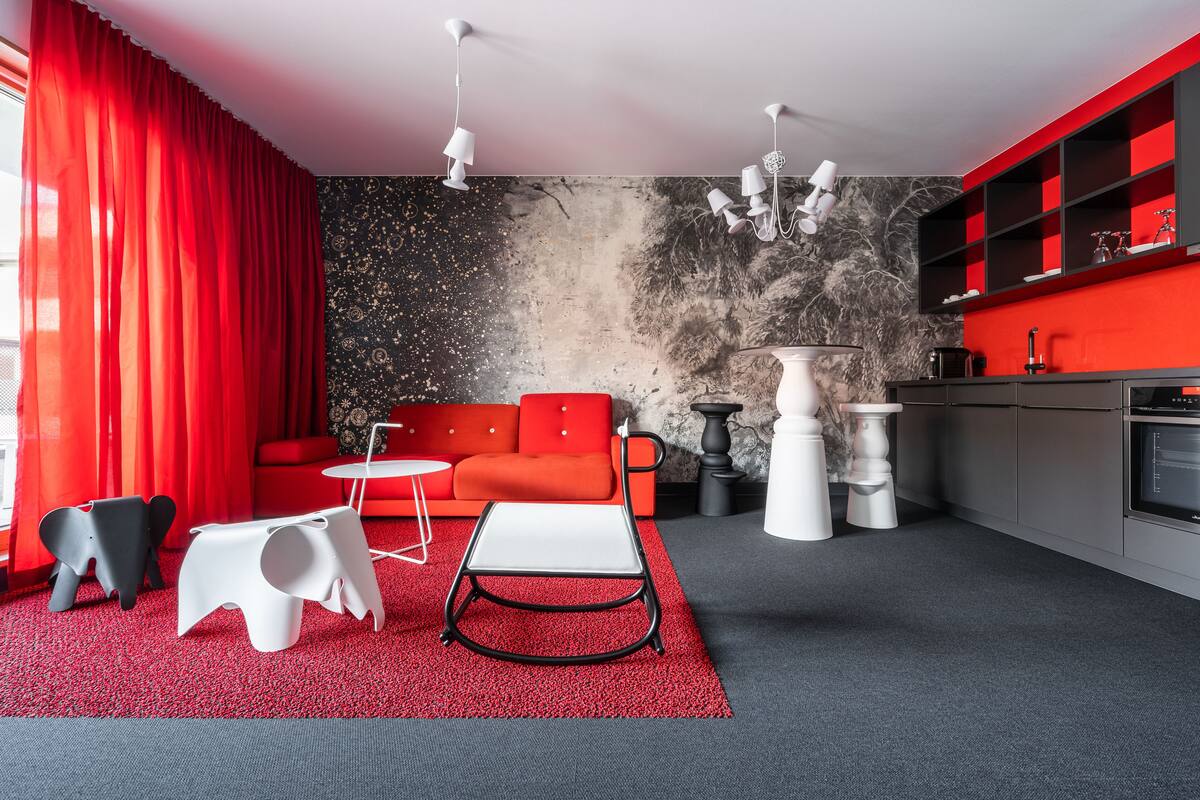 Un salon moderne avec un canapé rouge, une table basse blanche et des chaises noires et blanches.