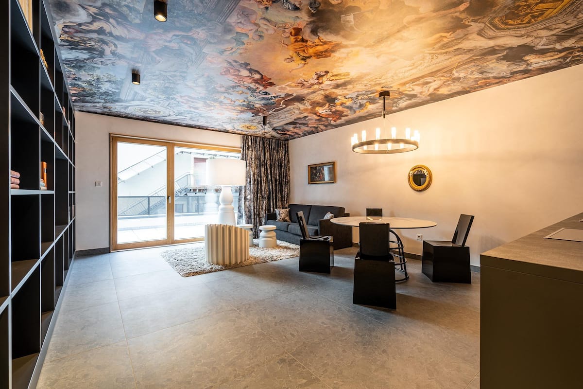 Un salon moderne avec une fresque murale haute, une table à manger ronde et un canapé.