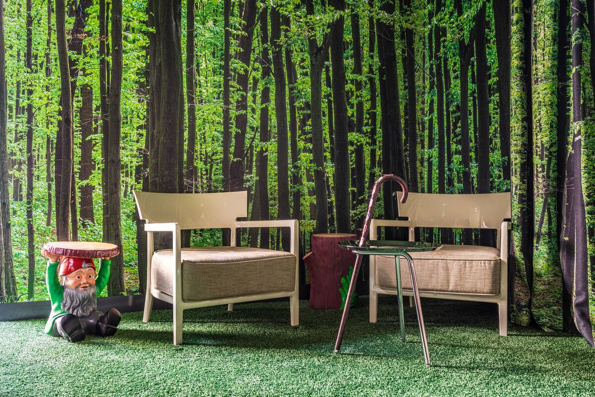 Une pièce avec deux chaises en bois et une petite table, le tout décoré d’un fond d’écran sur le thème de la forêt.