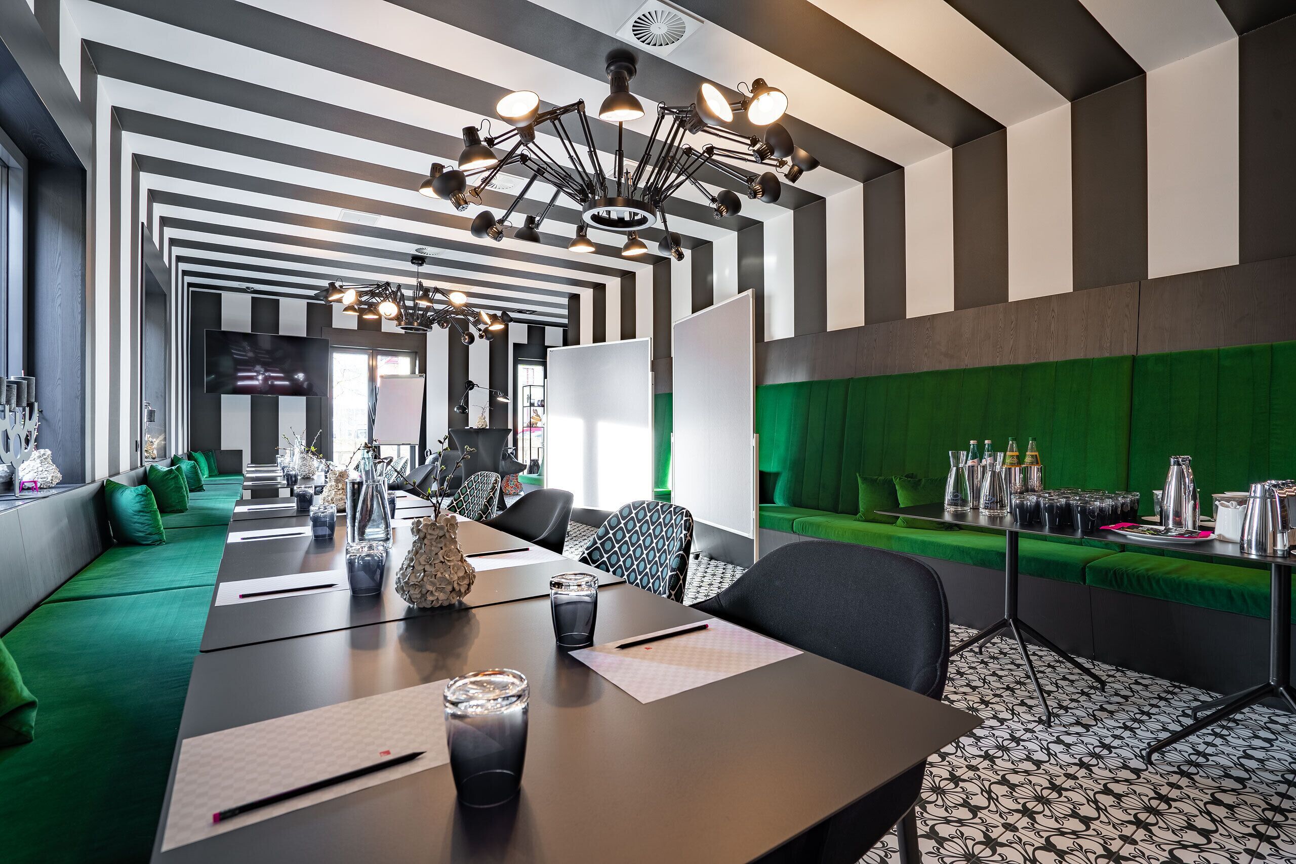 Una sala conferenze moderna con un lungo tavolo, sedute rivestite in verde e una parete decorata in tonalità verde.