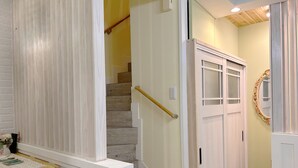Una escalera con peldaños de madera y barandilla blanca, que conduce a un rellano con una puerta blanca y un espejo.