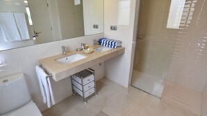 Ein modernes Badezimmer mit großem Spiegel, zwei Waschbecken, einer Dusche und einer Toilette.