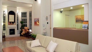 Een woonkamer met een beige bank, een teddybeer, een open haard en een klok aan de muur.