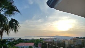 A balcony with a view of a swimming pool, palm trees, and distant buildings under a clear sky. - Villa Nunzia (Ercolano)