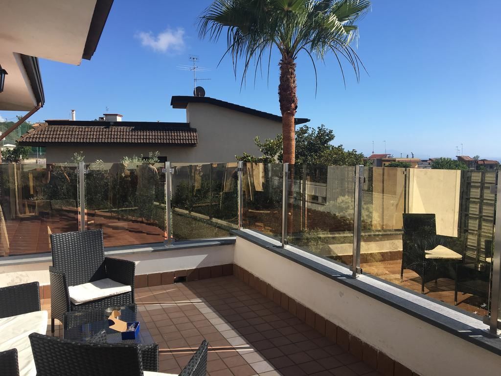 A balcony with outdoor furniture, a palm tree, and a view of neighboring buildings.