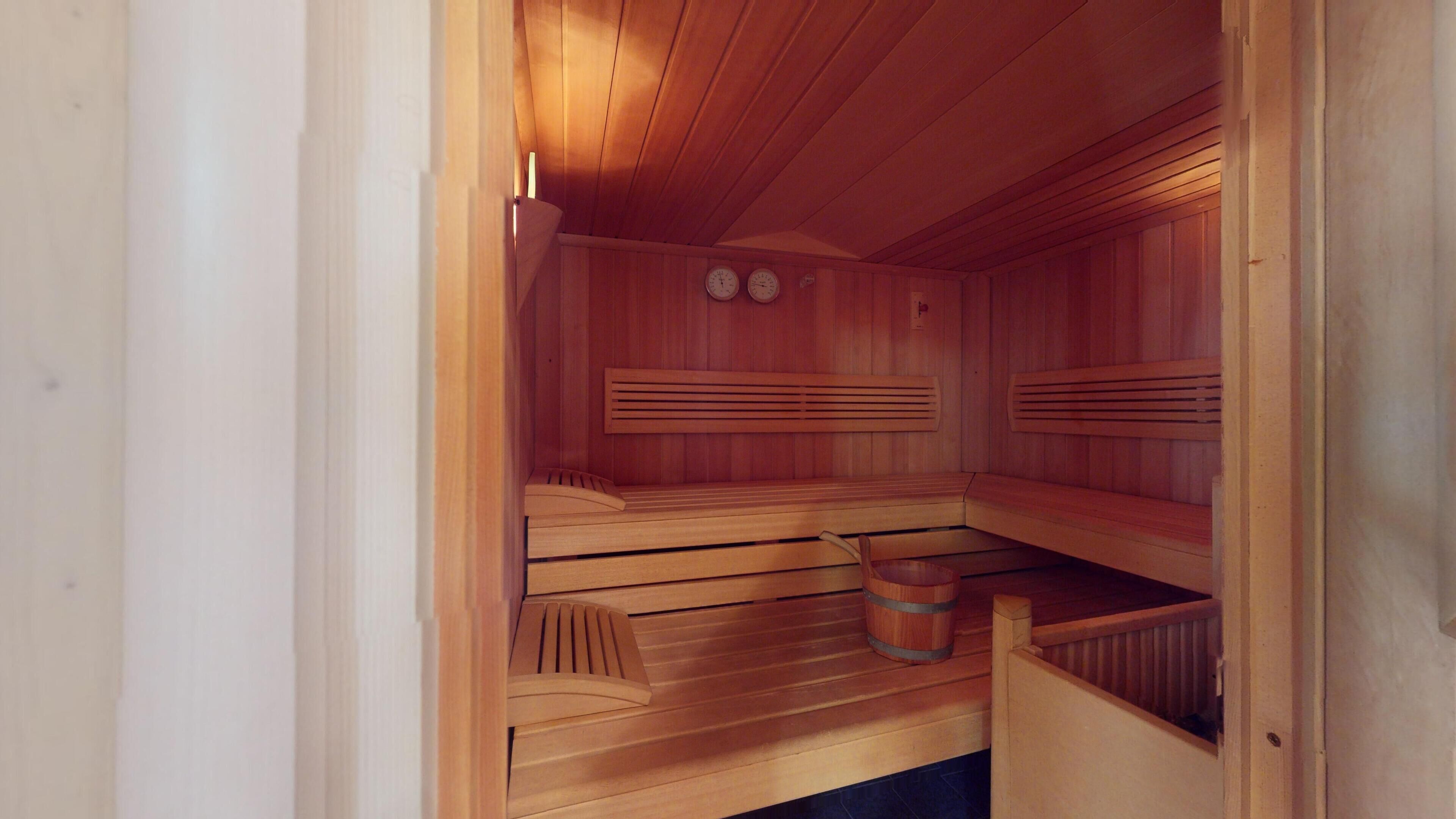 A wooden sauna with benches and a bucket.