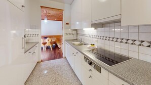 Una cocina moderna con armarios blancos, encimeras de granito y estufa empotrada.