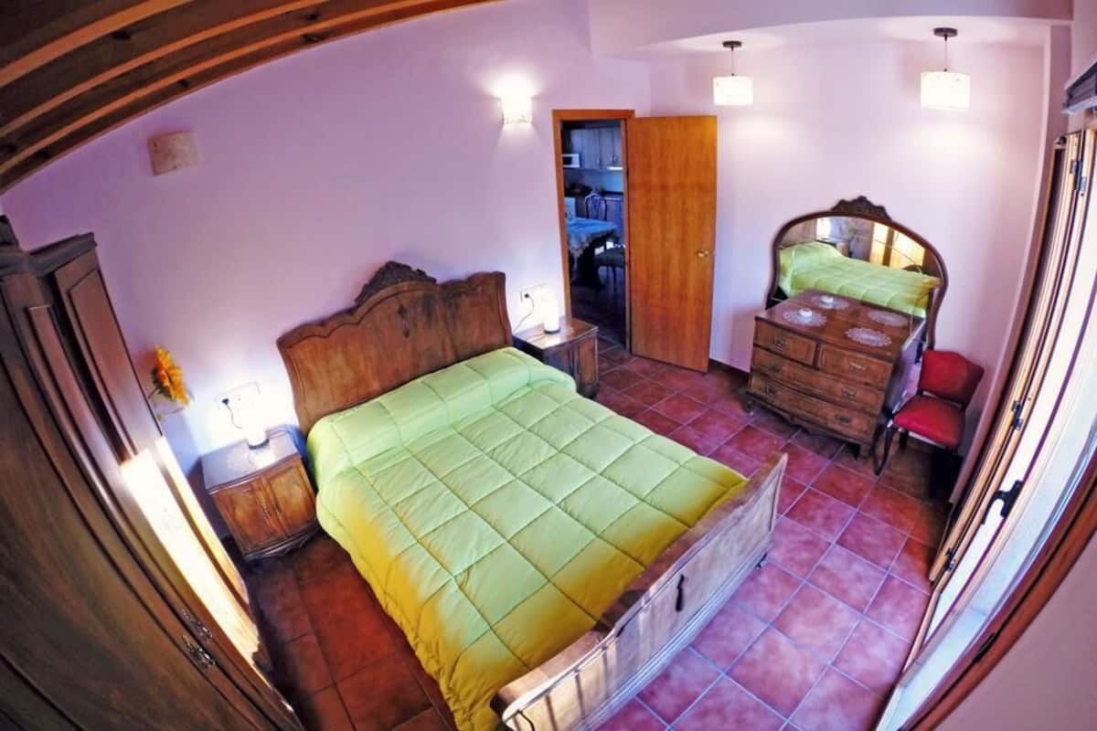A bedroom with a bed, wooden dresser, and a wardrobe.