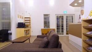 A hotel lobby with a sofa, a coffee machine, a bookshelf, and a reception desk. - Family Lodge Hatagoya Kisarazukou (Kisarazu)
