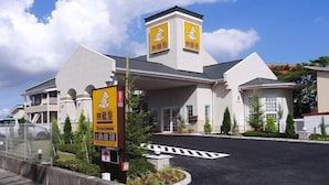A hotel with a prominent tower and signage, a parking area, and a clear sky. - Family Lodge Hatagoya Kisarazukou (Kisarazu)