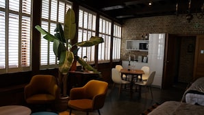 Una habitación acogedora con comedor, una planta grande y una cocina al fondo.