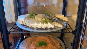 A food display case with various cheeses, grapes, and a salmon dish.
