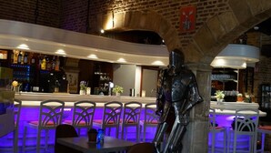 Un restaurante con pared de ladrillo, una zona de bar y una estatua de un caballero.