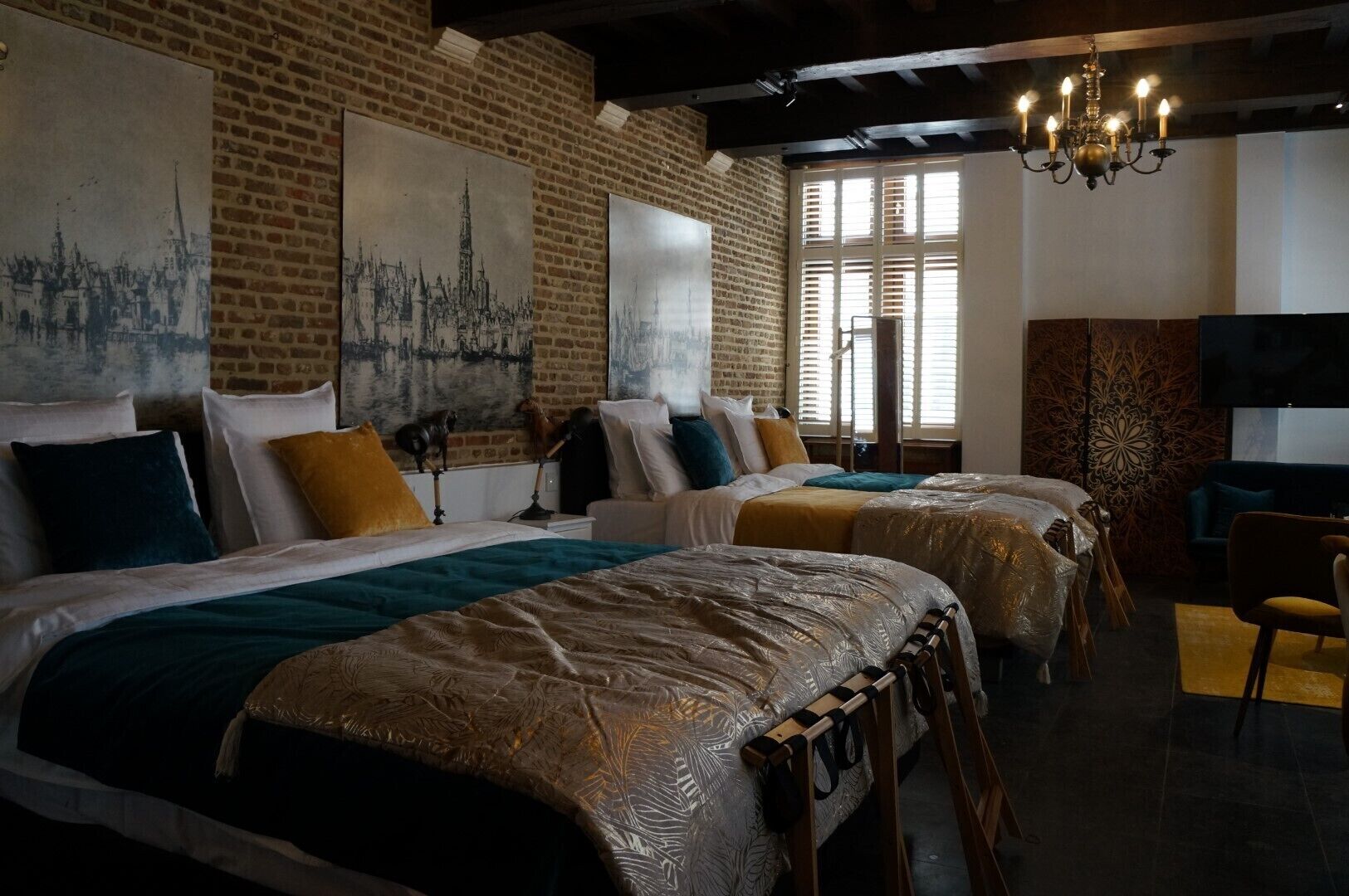 Een hotelkamer met twee bedden, een kroonluchter, een televisie en kunstwerken aan de wanden.