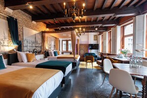 A hotel room with three beds, a dining table, and a chandelier. - Charming Suites Jan Zonder Vrees (Antwerp)