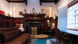 Una sala de estar acogedora con chimenea, muebles de madera y vistas al exterior a través de un ventanal.