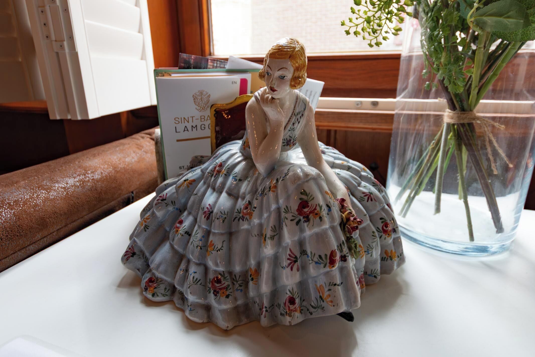 Une statuette représentant une femme vêtue d’une robe à motifs floraux, posée sur une table.