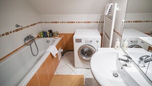 Une petite salle de bain équipée d’une baignoire, d’un lave-linge et d’un évier.