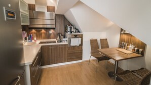 Une cuisine compacte dotée de meubles en bois, d’un réfrigérateur en acier inoxydable et d’un coin repas avec une table et des chaises.