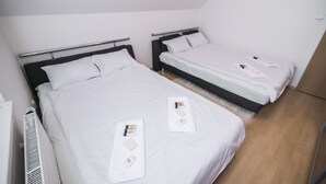 Une chambre d’hôtel avec deux lits, chacun étant équipé de draps et d’oreillers blancs. Des articles de toilette sont posés sur les lits.
