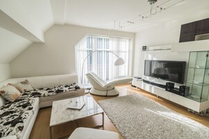 Una sala de estar moderna con un sofá, una mesa de centro, un televisor y un aparador de vidrio.