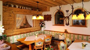 A traditional dining area with wooden furniture, a chandelier, and a deer antler decoration. - Hotel Viktoria & Landhaus Joggl (Mayrhofen)