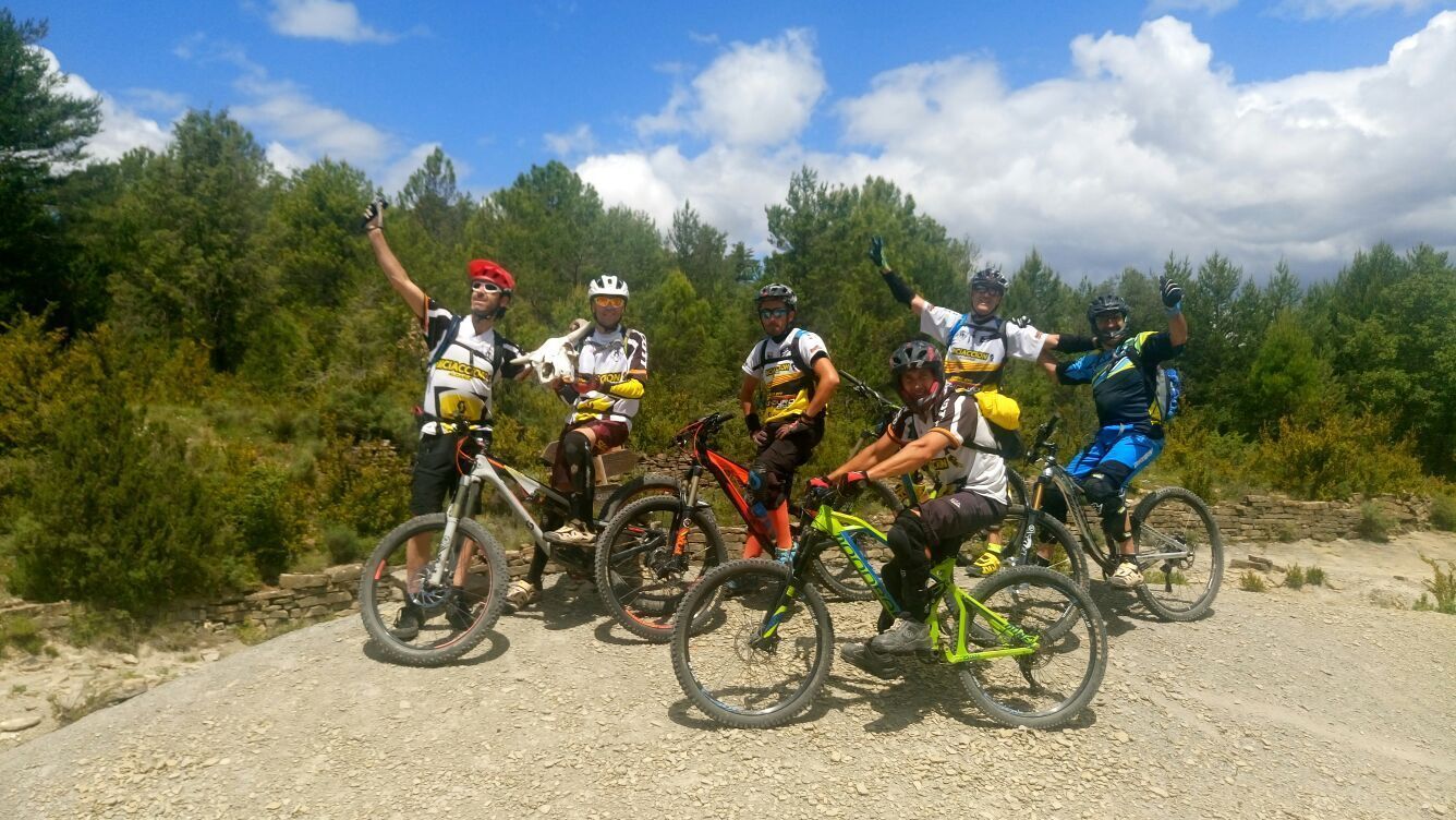 Un grupo de ciclistas en un sendero de tierra con árboles al fondo.