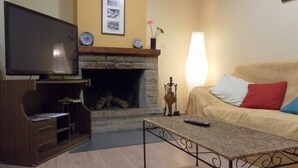 Una sala de estar con televisión, chimenea, sofá y mesa de centro.