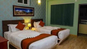 Quarto de hotel com duas camas, um quadro com vista para o céu noturno, uma janela com cortinas e uma pequena cozinha.