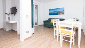 Een moderne woonkamer met een groene bank, een witte eettafel en gele stoelen.