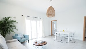 Ein modernes Wohnzimmer mit Sofa, Couchtisch und Essbereich mit Tisch und Stühlen.