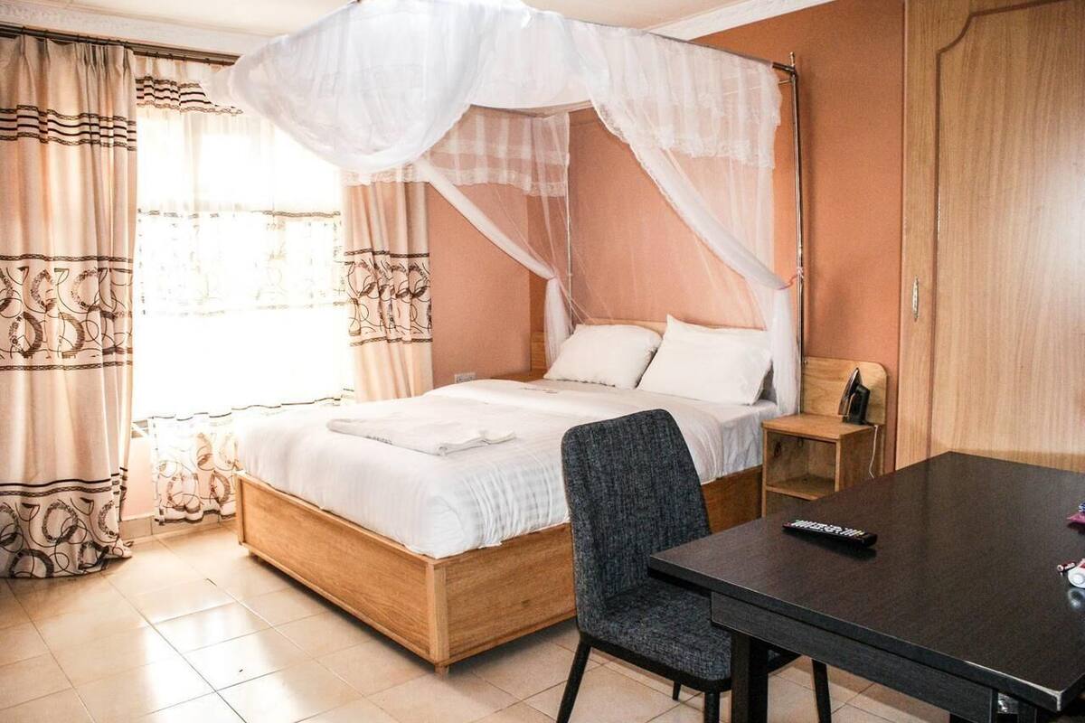 Un dormitorio con cama con dosel, mesita de noche, una silla y televisor.