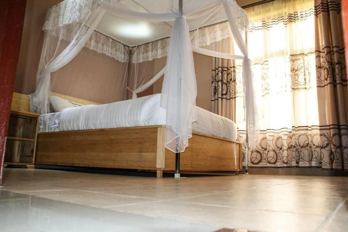 Una cama con dosel, cabecera de madera y mesita de noche.