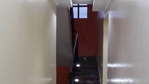 A corridor with a staircase leading to an upper floor. The walls are plain with a tiled floor. - Twiggs Hotel (Bomet)