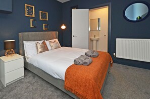 A bedroom with a bed, nightstand, and a bathroom visible through an open door.