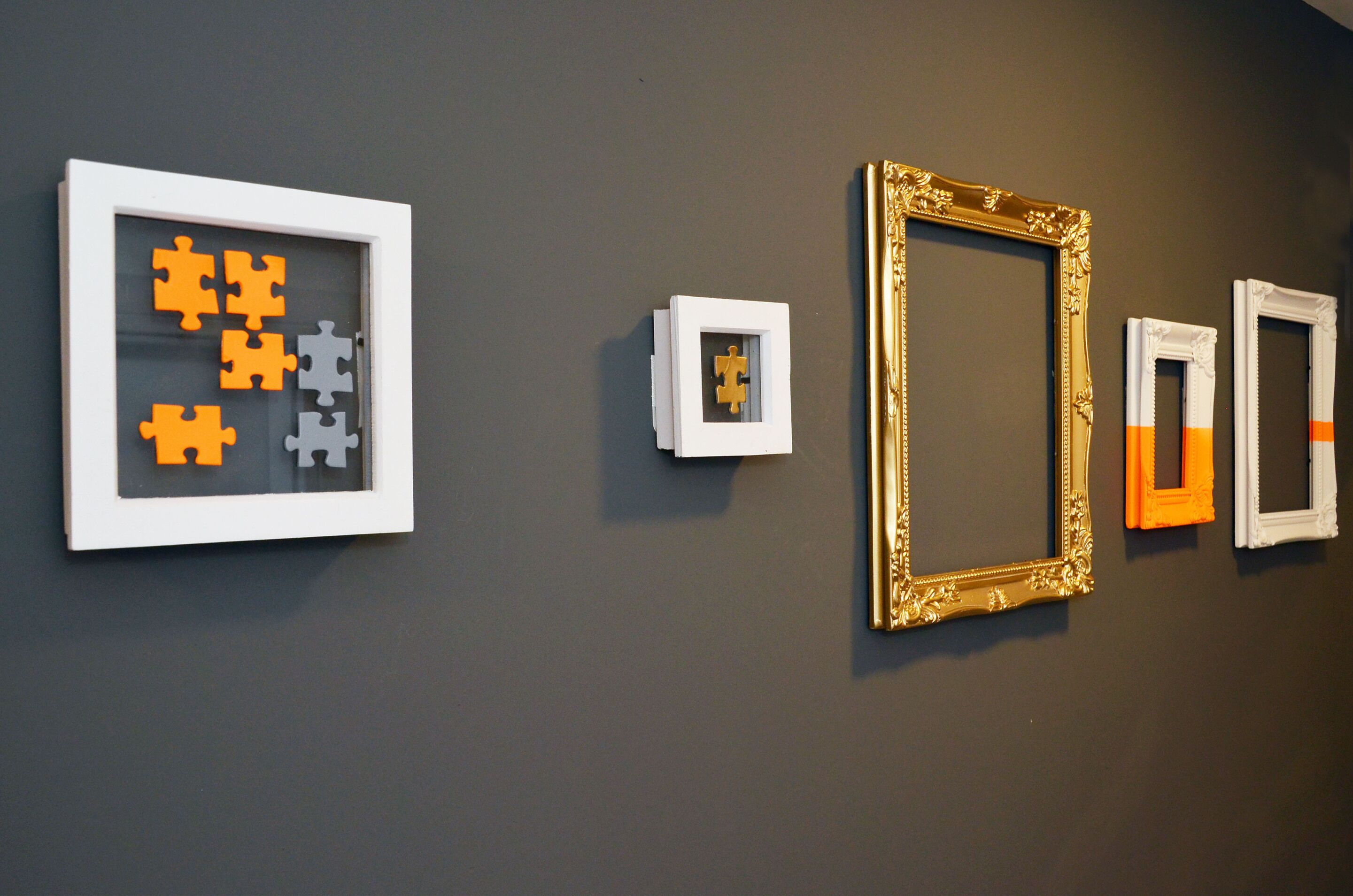 A wall with various framed artworks and a puzzle piece display.
