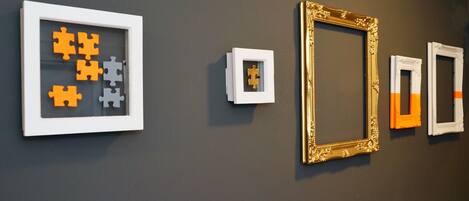 A wall with various framed artworks and a puzzle piece display.