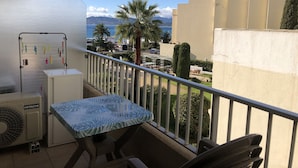 Ein Balkon mit Tisch und Stühlen, einer Wäscheleine und Blick auf das Meer und Gebäude.