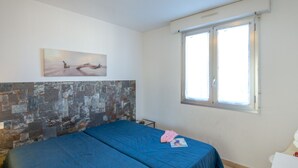 A bedroom with a bed, a window, a painting, and a wall with a textured pattern.