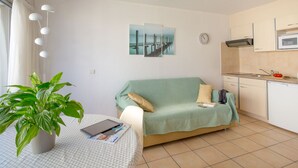 A compact living space with a kitchenette, a dining area with a table and chairs, and a green sofa.
