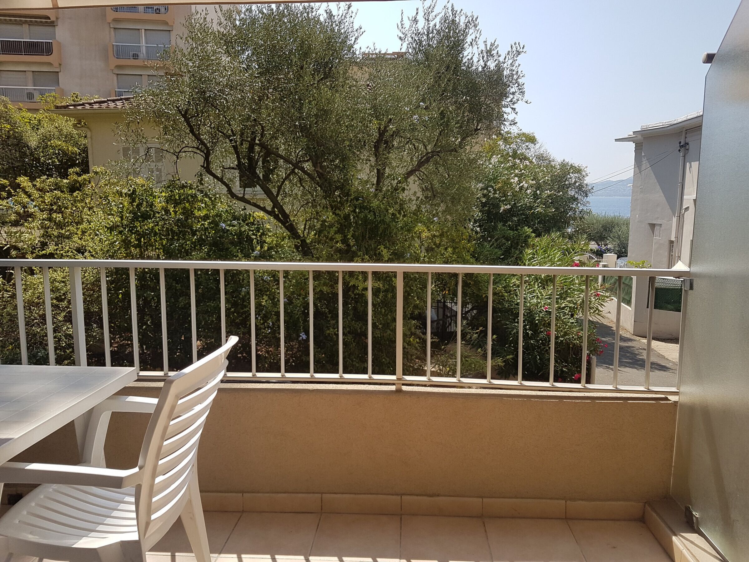 Un balcon avec une balustrade blanche, une table et deux chaises.