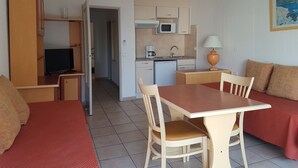 Une chambre d’hôtel compacte comprenant un coin cuisine, un espace repas et un coin salon.
