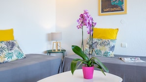 A room with two beds, a table with a potted plant, a lamp, and a poster on the wall.